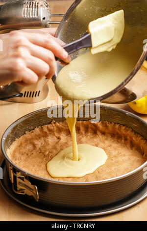 Zwei weiblichen kaukasischen Hände gießen Käsekuchen Creme in einen schwarzen Backblech, backen Geschirr in den Hintergrund - Seitenansicht, Hochformat Stockfoto