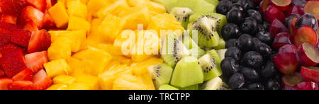 Ein Hintergrund der Regenbogenfarbenen Obstsalat in Zeilen Stockfoto