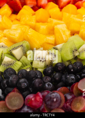 Ein Hintergrund der Regenbogenfarbenen Obstsalat in Zeilen Stockfoto