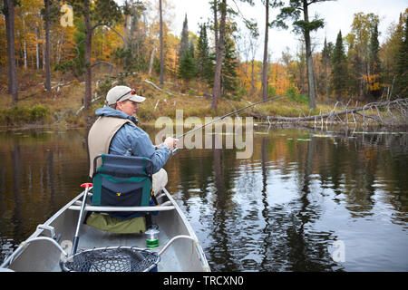 40 s kaukasischen Fischer fischen von einem Kanu auf dem See im nördlichen Minnesota im Herbst Stockfoto