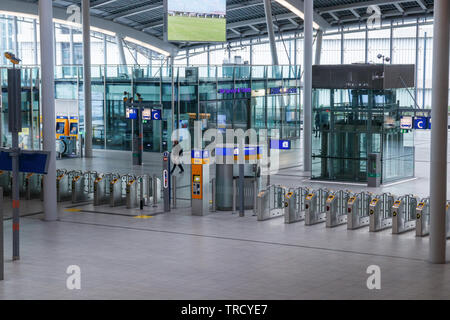 Einsamer Reisender, der zu einer Reihe von Fahrkartensperren in der adesolaten Centraal Bahnhofshalle läuft. Utrechter, Niederlande. Stockfoto