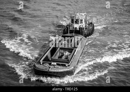 Tug Boat drücken eine Verschwendung Schiff auf der Themse in London. Stockfoto