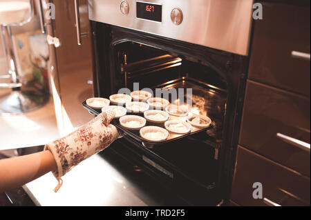 Frau Teig für Muffins im Ofen in der Küche Nahaufnahme. Kochzeit. Stockfoto