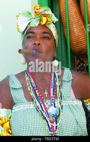 Farbenfroh kubanischen Dame Rauchen eine große Zigarre in einer der Gassen in der Altstadt von Havanna, Kuba, Karibik gekleidet Stockfoto