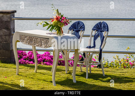 Aus Holz geschnitzte Unterzeichnung Tabelle mit tropischen Blumen Bouquet und Stühle für eine Zeremonie. Blick auf das Meer. Konzept einer Hochzeit. Bali, Indonesien. Stockfoto