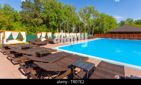 Pool und Spa Resort. Luxus am Pool mit Sonnenliegen und Liegestühlen und Palmen über blaue Meer. Ruhigen Luxus Ferienhäuser Hintergrund. Stockfoto