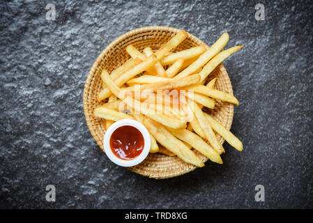 Pommes frites auf Korb mit Ketchup auf dunklem Hintergrund Stockfoto