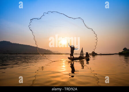 Asien Fischer net auf hölzernen Boot casting net Sonnenuntergang bzw. Sonnenaufgang in den Fluss Mekong/Silhouette Fischerboot mit Berg Hintergrund Menschen Stockfoto