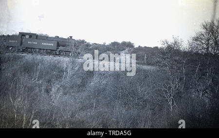 1950, historisch, eine Dampflokomotive der British Railways 69813, die auf einer Steigung eine Eisenbahnstrecke hinunterfährt, England, Großbritannien. Diese Schwerlastlokomotive wurde 1911 im Werk Gorton für die Great Central Railways (GCR), später die LNER (London & North Eastern Railway) gebaut. - Unter der Aufsicht von John G. Robinson und blieb im Dienst bis 1960, als es zurückgezogen wurde, als Dampf abnahm und die Beeching Schnitte des Eisenbahnnetzes. Stockfoto