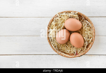 Huhn Eier im Korb Nest auf weißem Holz- Hintergrund Stockfoto