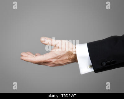 Nahaufnahme eines leeren offenen Hand in einem schwarzen Anzug gegen grauer Hintergrund Stockfoto