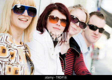 Group Portrait / Seitenansicht von 4 jungen Personen tragen Sonnenbrillen saßen und in die Kamera Stockfoto