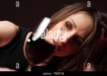 Porträt einer depressiv und alcoholised Frau ihren Kopf auf ihre Hand mit einem Glas Wein Stockfoto