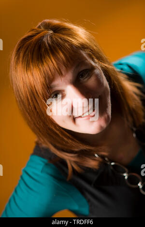 Porträt eines sympathischen Frau mittleren Alters mit roten Haaren gegen braunen Hintergrund Stockfoto