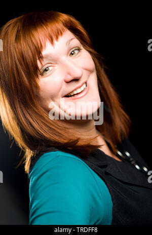 Porträt eines sympathischen Frau mittleren Alters mit roten Haaren auf schwarzem Hintergrund Stockfoto