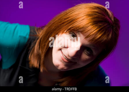 Porträt eines sympathischen Frau mittleren Alters mit roten Haaren gegen lila Hintergrund Stockfoto