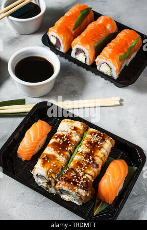 Verschiedene Arten von Sushi am konkreten Hintergrund serviert. Stockfoto
