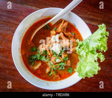 Curry Suppe Schweinefleisch Knochen mit Kokosmilch und Kräuter Gewürze würzig in Schüssel auf Holz- Hintergrund Stockfoto