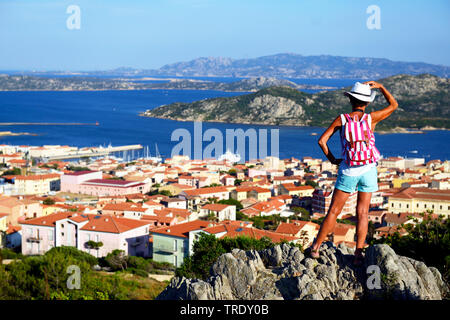 Weibliche touristische steht auf einem Felsen und Blick in die Küstenstadt, Maddalena, Italien, Sardinien, Palau Stockfoto