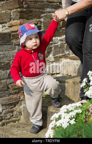 Porträt eines Jungen zu Fuß über Treppen mit einer Hand halten, von einem Erwachsenen Stockfoto