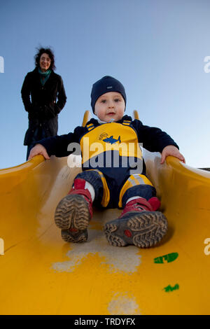 Porträt eines Jungen auf einer Rutschbahn mit seiner Mamma beobachten Stockfoto