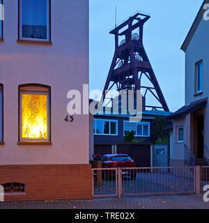 Wohnhäuser mit dem Fördergerüst der Zeche Pluto in der Dämmerung, Deutschland, Nordrhein-Westfalen, Ruhrgebiet, Herne Stockfoto