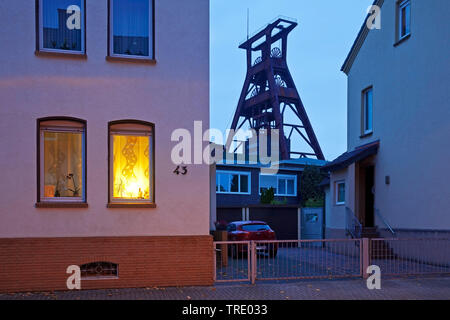 Wohnhäuser mit dem Fördergerüst der Zeche Pluto in der Dämmerung, Deutschland, Nordrhein-Westfalen, Ruhrgebiet, Herne Stockfoto