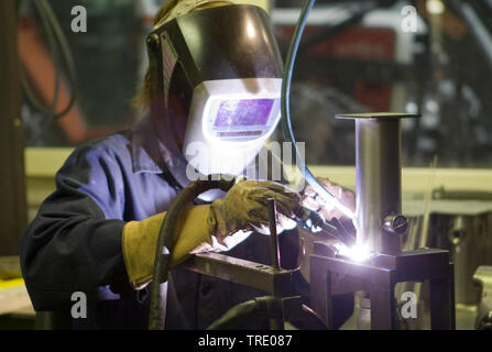 Arbeiter mit Schutzkleidung und Helm befestigt werden Schweißer WIG Schweißen Schutzschild durchführen Stockfoto