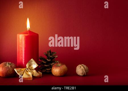 Advent Dekoration mit brennenden Kerze auf rotem Hintergrund Stockfoto