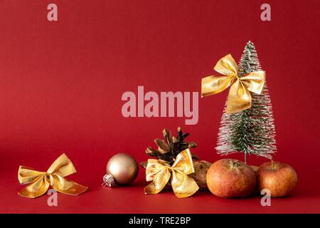 Weihnachtsdekoration mit Baum, Bälle, Bänder und Äpfel auf rotem Hintergrund Stockfoto