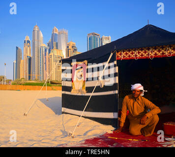 Bedouin Mann und sein Lager vor der Wolkenkratzer in Dubai, Vereinigte Arabische Emirate, Dubai Stockfoto