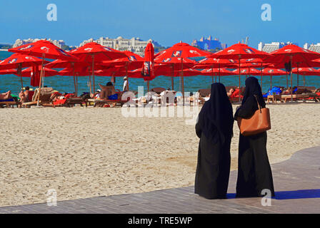 Zwei Frauen mit traditionellen Burkas auf dem Strand von Marina Dubai, Vereinigte Arabische Emirate, Dubai Stockfoto