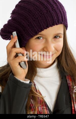 Portrait einer jungen sympathischen Mädchen, dass eine Mobile an Ihr Ohr und lächelnd in die Kamera Stockfoto