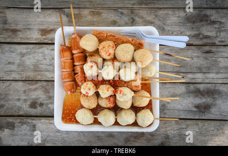 Das Essen im Thai Stil von gegrillten Würstchen Würstchen fleisch und fisch Kugel Kugel in Stick auf Tablett mit Holz- Hintergrund Stockfoto