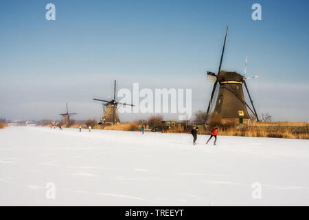 Eislaufen auf zugefrorenen Kanal vor die Windmühlen von Kinderdijk, Niederlande, Kinderdijk Stockfoto