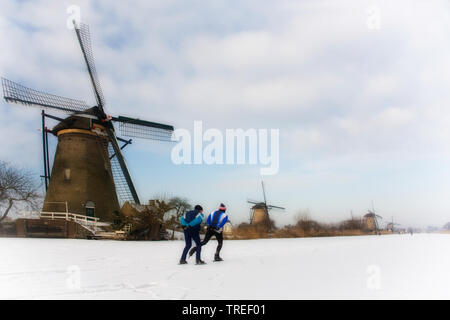 Eislaufen auf zugefrorenen Kanal vor die Windmühlen von Kinderdijk, Niederlande, Kinderdijk Stockfoto