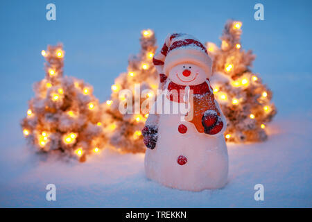 Schneemann und kleine Beleuchtete Weihnachtsbäume im Schnee Stockfoto