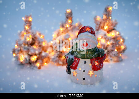 Schneemann und kleine Beleuchtete Weihnachtsbäume im Schnee Stockfoto