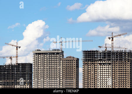 Baukräne und Wohnhochhäuser im Bau auf dem Hintergrund der blauen Himmel mit weißen Wolken Stockfoto