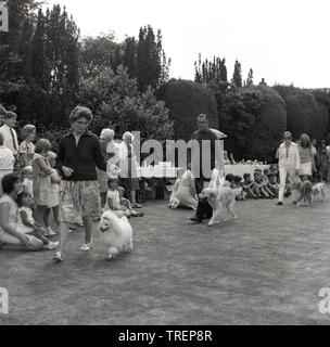 1967, historisch, auf einem Dorffest sitzen Familien und Kinder und beobachten eine Hundeschau, Besitzer gehen mit ihren Hunden, Waddesdon, Buckinghamshire, England, Großbritannien. Stockfoto