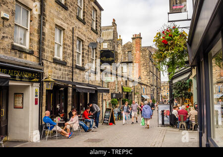 Die Menschen genießen einen warmen Herbst Tag in einer gepflasterten Straße, gesäumt von Restaurants und Geschäfte in Harrogate, England, UK. Stockfoto