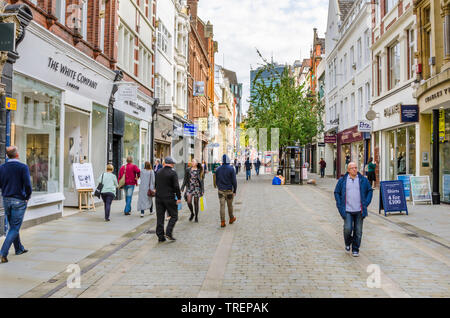 Käufer und Touristen um die King Street bummeln im Zentrum von Manchester, Großbritannien, an einem warmen Herbsttag Stockfoto