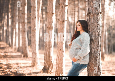 Schöne schwangere Frau 30-35 Jahre alten tragen gemütlichen Pullover im Freien. Freuen Uns. Herbst Saison. Stockfoto