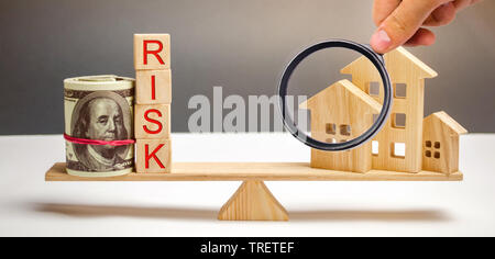 Geld beutel, Blöcke mit dem Wort Risiko und ein Holzhaus auf der Waage. Das Konzept, Geld zu verlieren, wenn Sie in Immobilien investieren. Risiken der Verlust eines Ho Stockfoto