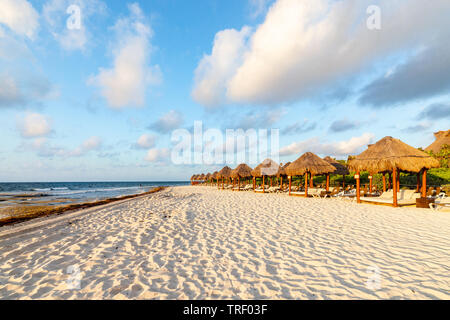 Blick auf den Strand mit Beach Cabanas auf der rechten Seite und das Meer auf der linken Seite mit einem blauen Himmel und Wolken Overhead. Stockfoto