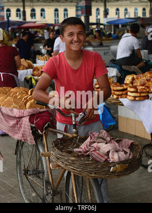 Margilan, Fergana-tal, Usbekistan - 4. Juni 2019: Junge Männer verkaufen USBEKISCHEN Brot, nicht oder lepeshka, die rund und flach und wird im tandyr, in Stockfoto