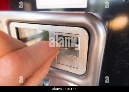 Person treibt ein 20 p Münze in den Schlitz der späten Modell Münze öffentliches Telefon/Handy in original Rot/call-Box betrieben werden. (99) Stockfoto