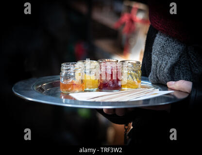 Frau mit einem Fach und Wartung für Geschmack, köstliche hausgemachte Frucht Orange, Erdbeere Marmeladen. Stockfoto