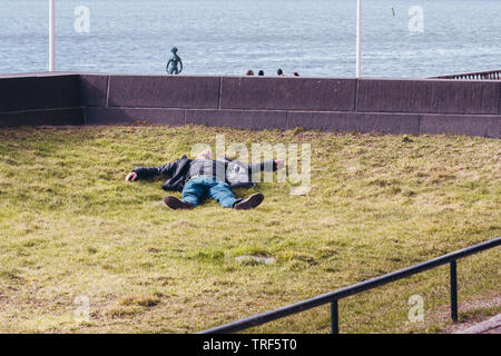 Editorial 03.27.2019 Stockholm Schweden Mann Festlegung draußen im Gras auf einem warmen Frühling Tag Stockfoto