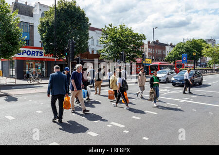 Käufer auf einen Fußgängerüberweg auf Holloway Road, Islington, London, UK Stockfoto